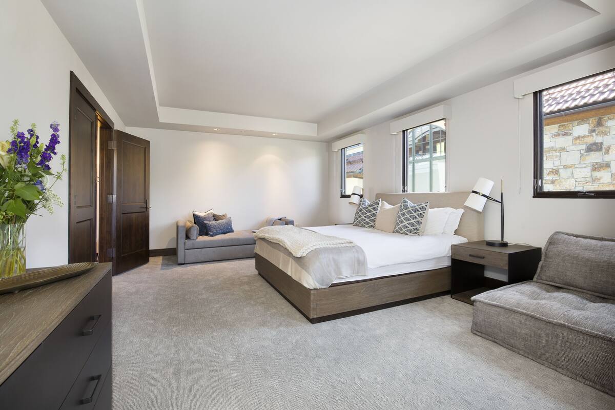 A modern bedroom with a large bed, a sofa, a nightstand, and a dresser.