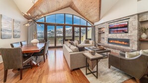 A spacious living area with a fireplace, large windows, and a high ceiling. - Relais & Châteaux Lumière by Dunton (Telluride)