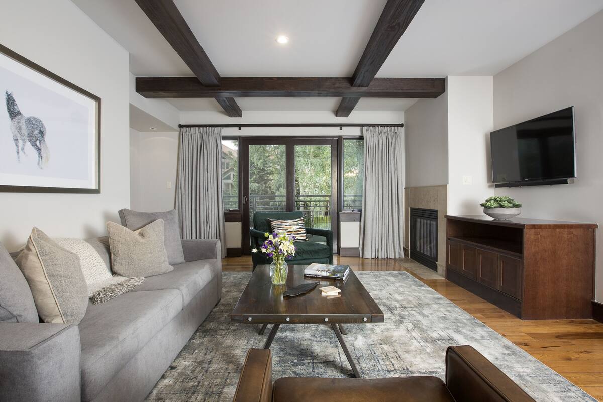 A modern living room with a grey sofa, a coffee table, and a TV mounted on the wall.
