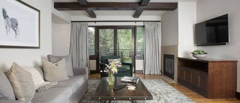 A modern living room with a grey sofa, a coffee table, and a TV mounted on the wall.
