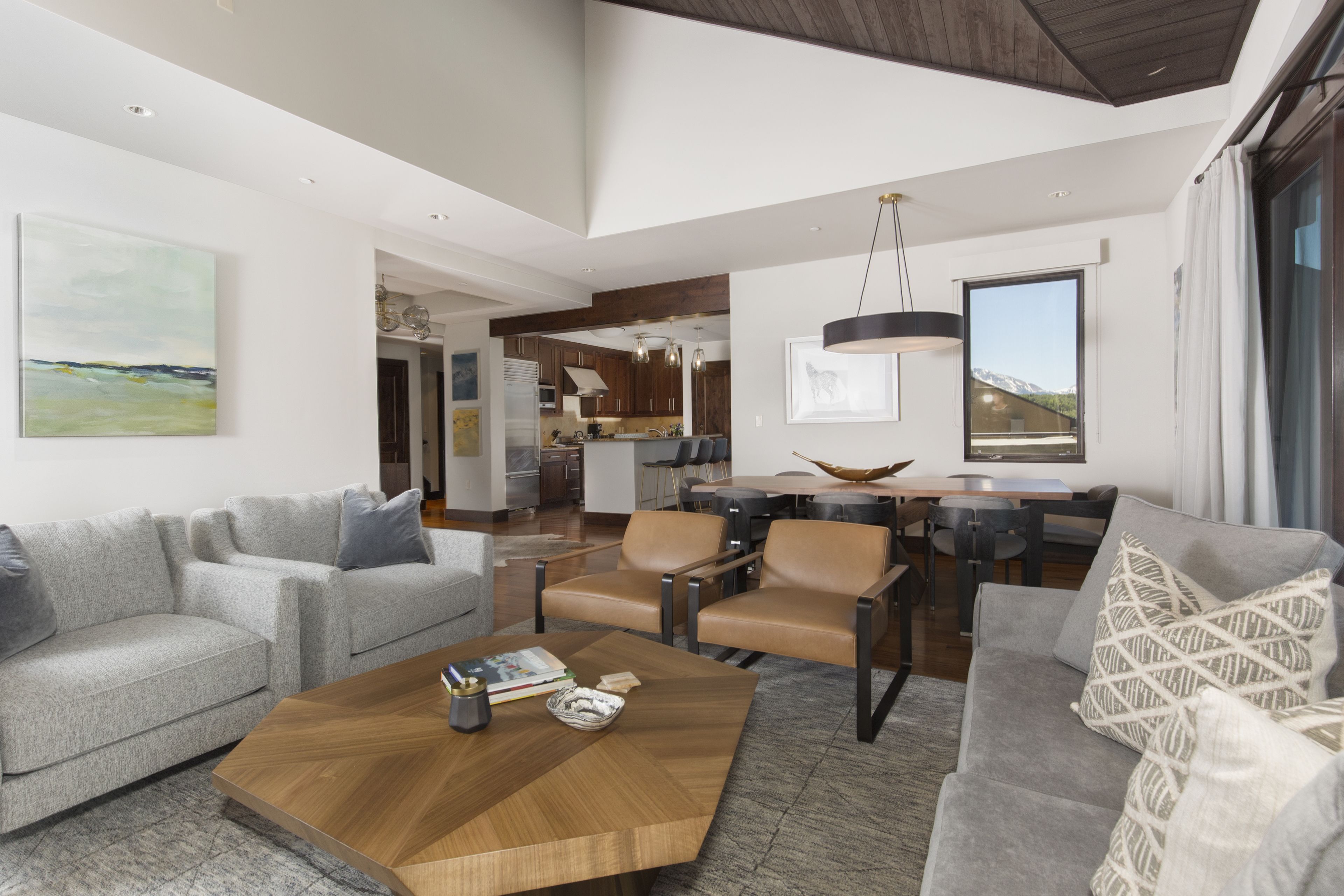 A modern living room with a grey sofa, a wooden coffee table, and a dining area with a round table and chairs.
