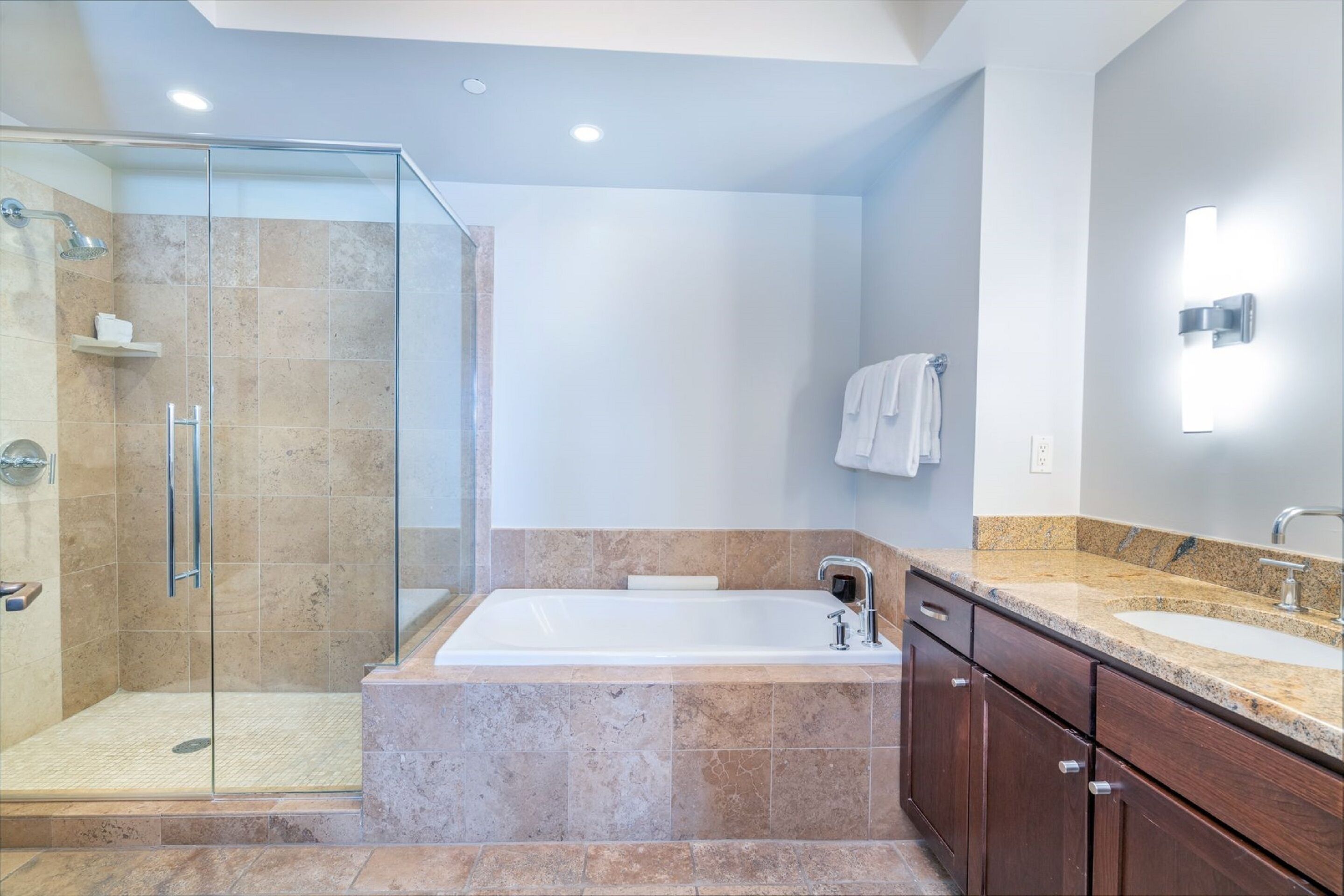 Une salle de bain moderne dotée d’une douche à parois de verre, d’une grande baignoire sur pied et d’un meuble-lavabo à deux vasques.