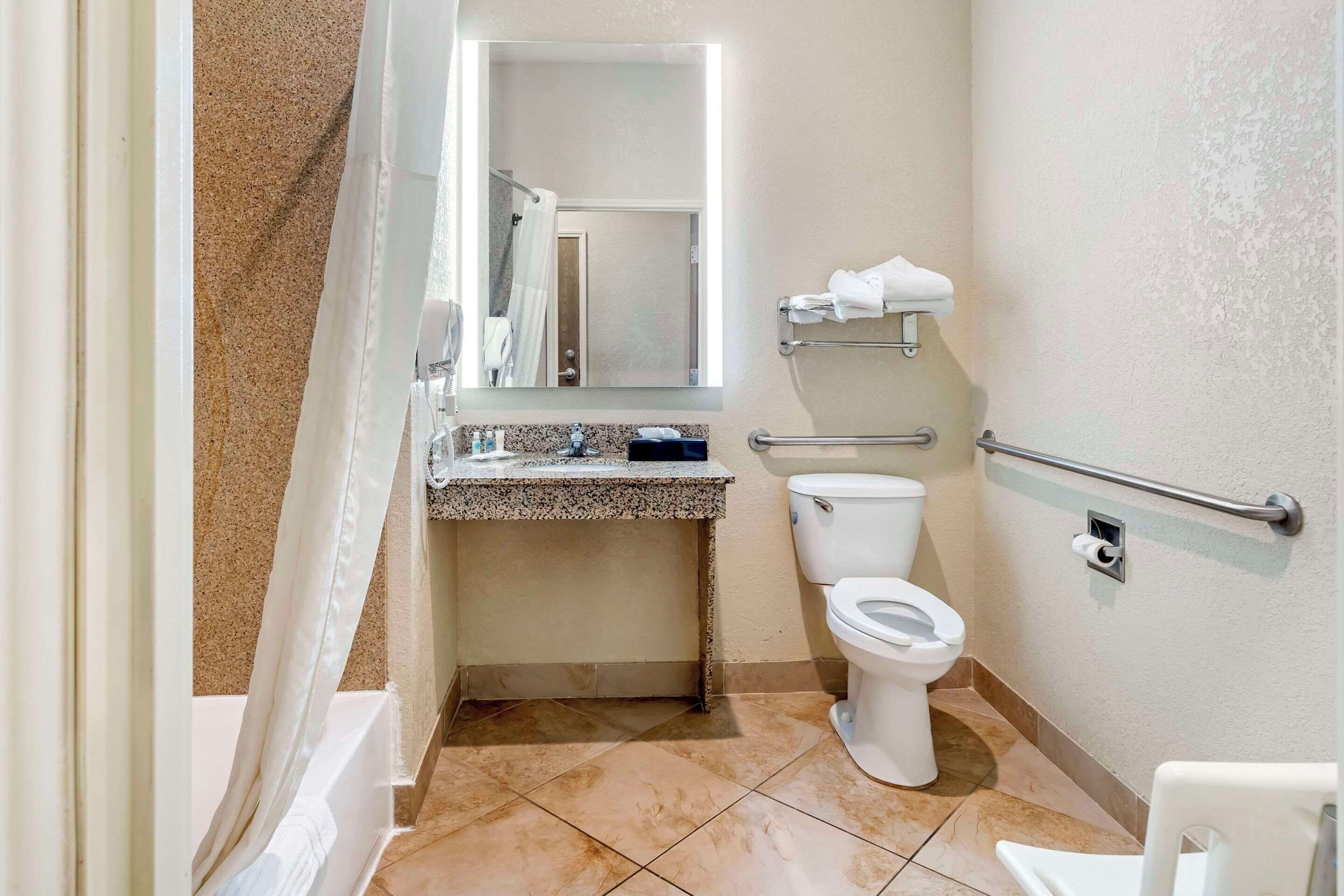 Un baño pequeño con inodoro, lavamanos con espejo y zona de ducha.