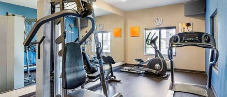 A gym with exercise equipment, a treadmill, and a mirror.