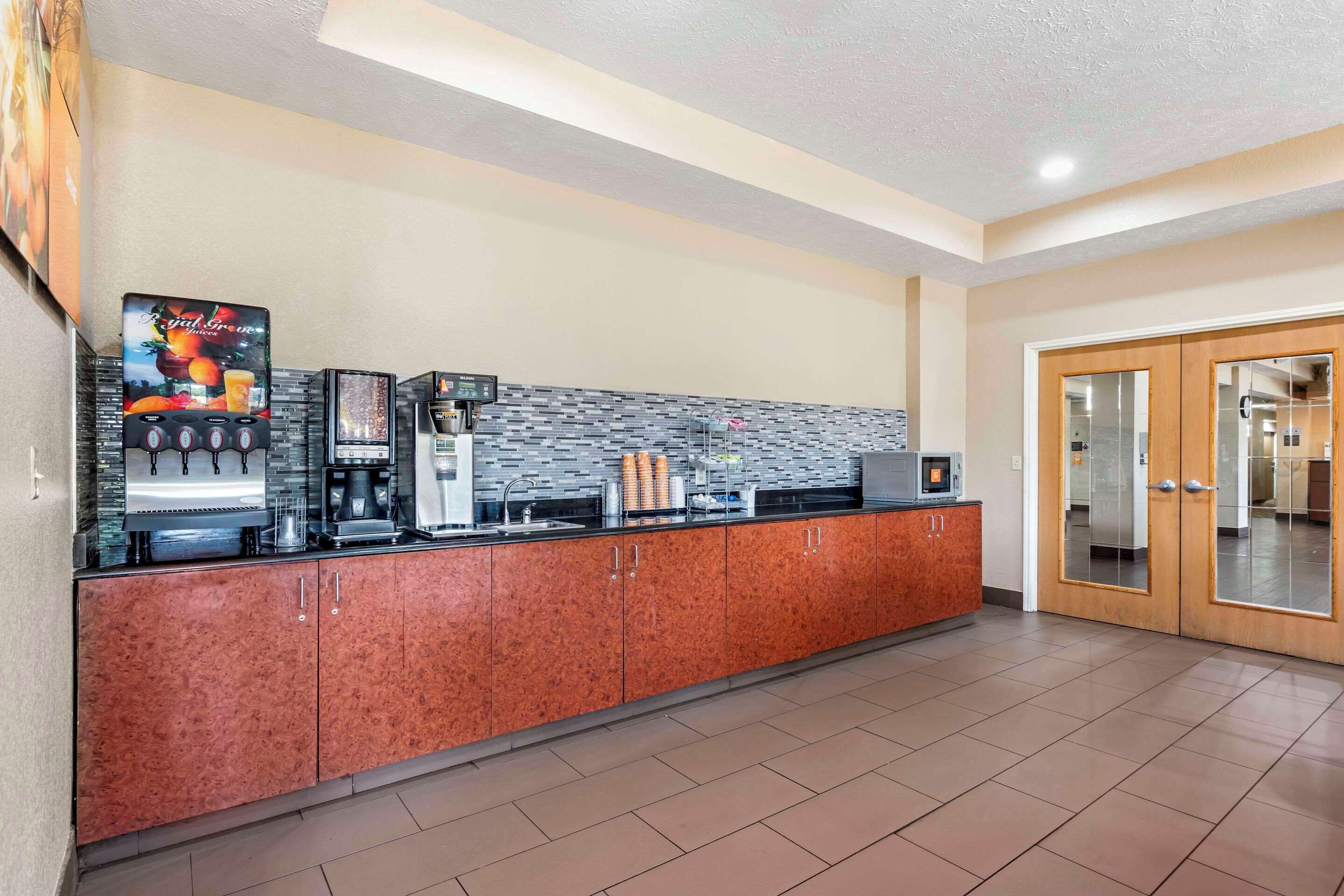 A modern kitchen area with a coffee station, a microwave, and a refrigerator.