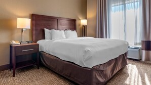 A hotel room with a large bed, two bedside lamps, a nightstand with a phone, and a window with curtains.