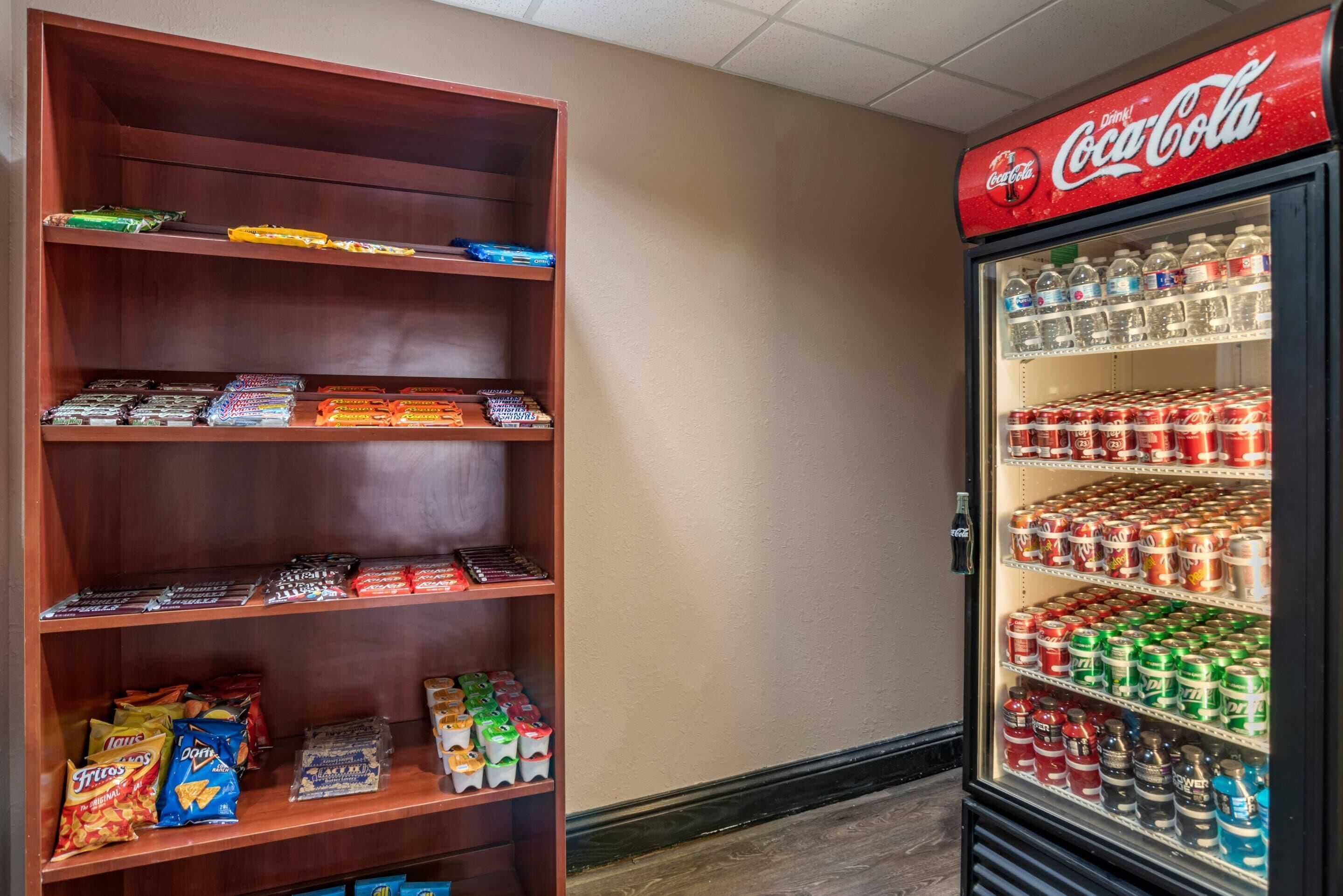 A vending machine stocked with Coca-Cola and Pepsi, and a wooden shelf with snacks and drinks.