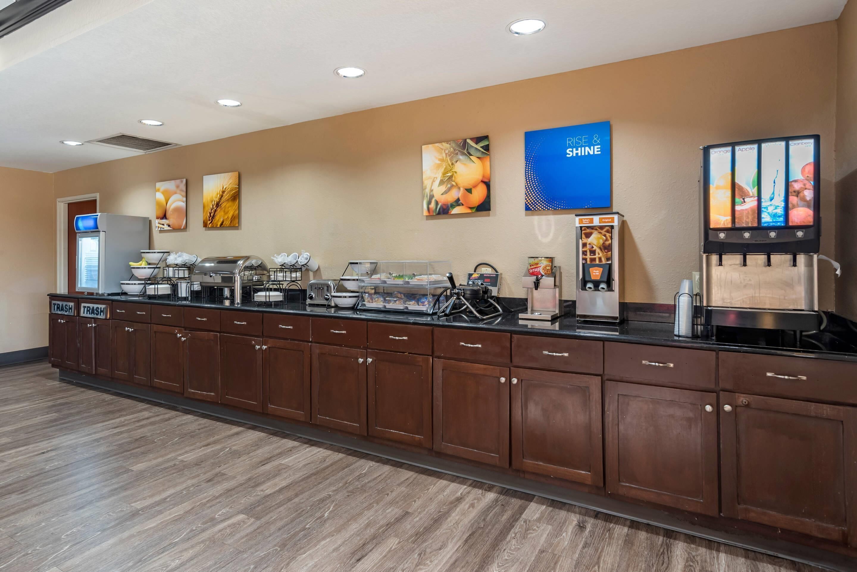 A buffet setup with various food stations, a trash bin, and a coffee machine.