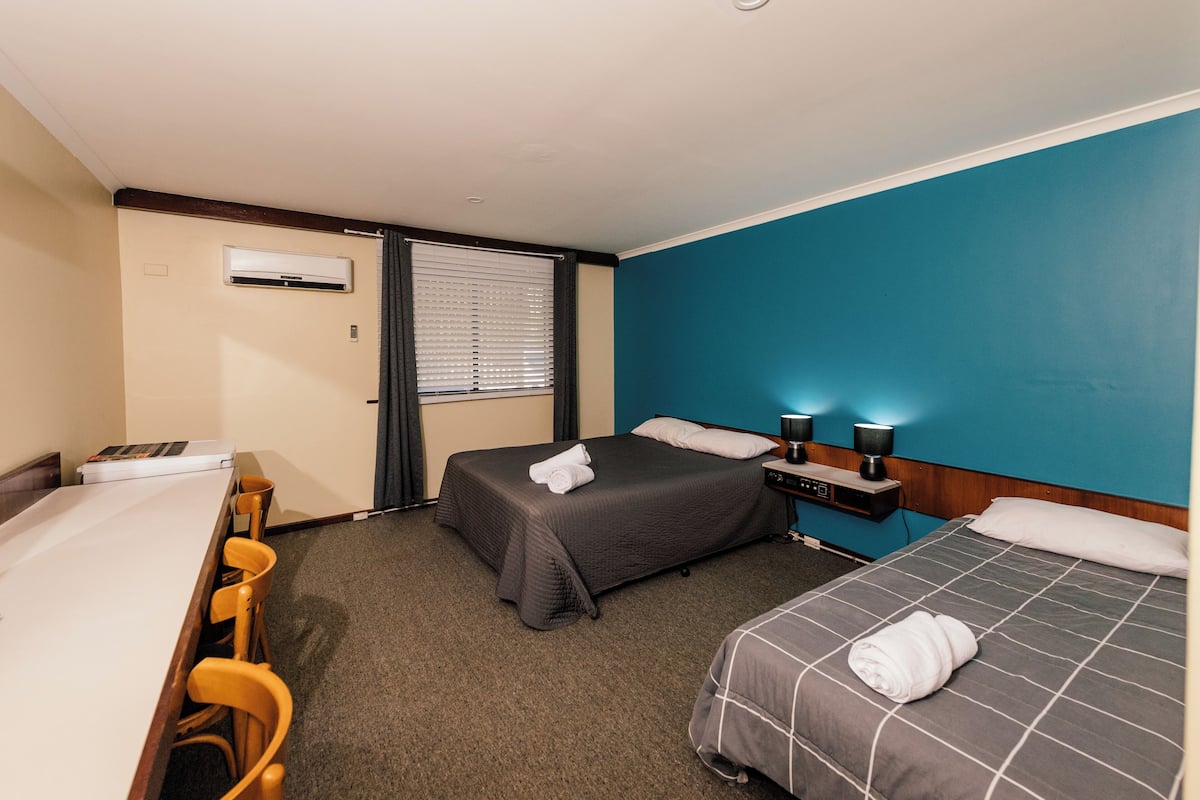 Habitación de hotel con dos camas, un escritorio y una silla.