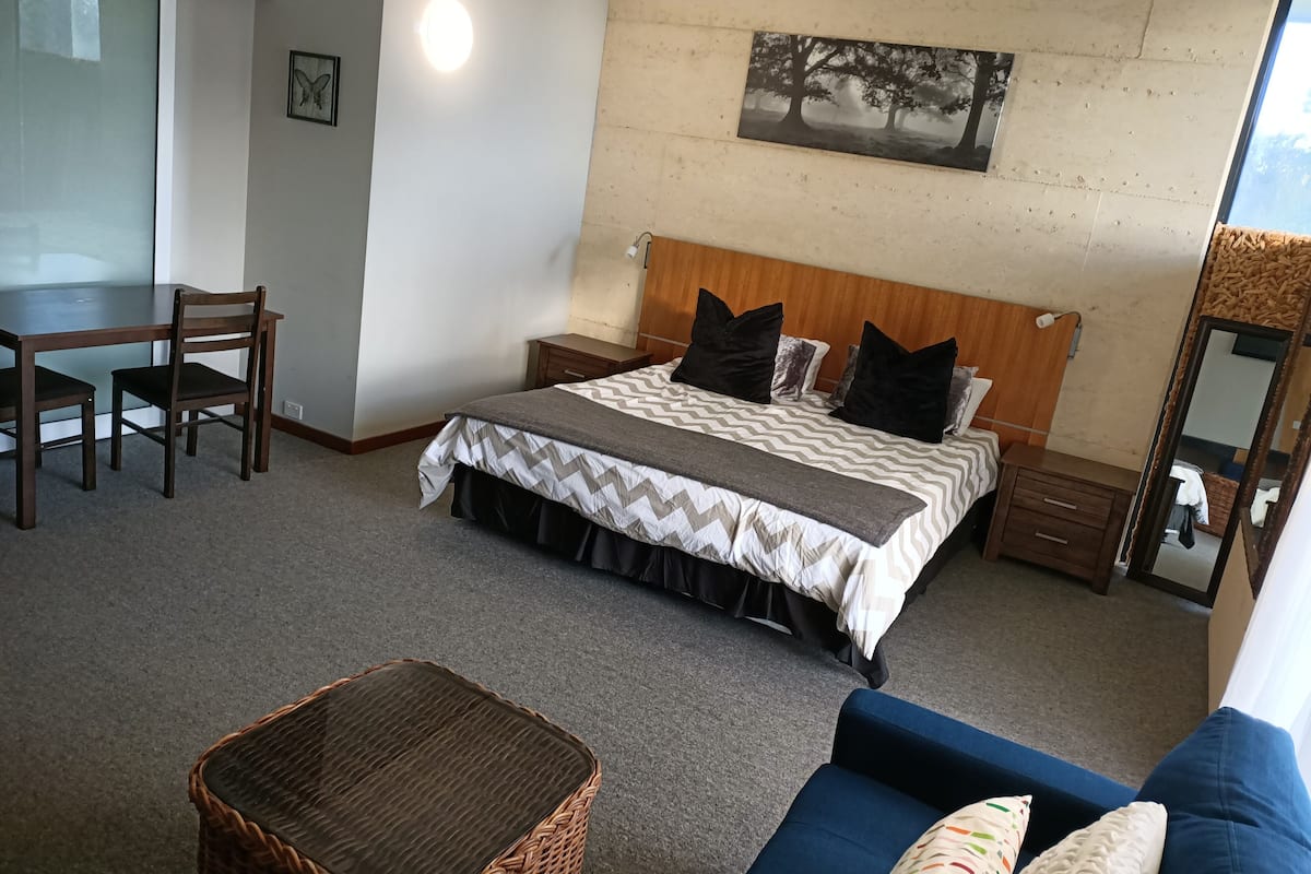 Un dormitorio con cama, mesitas de noche, un escritorio y una silla.