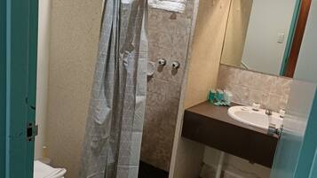 A bathroom with a shower curtain, toilet, sink, and tiled floor.