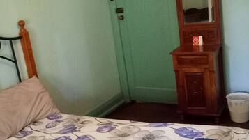 A bedroom with a bed, a wooden dresser, a mirror, and a door.