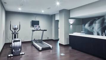Een moderne sportschool met cardioapparatuur, een grote spiegel en een receptie.