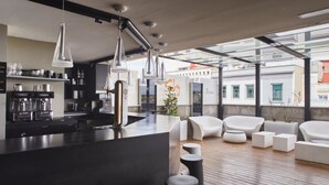 A modern kitchen with a central island, pendant lighting, and a view of the city through large windows. - Hotel Silken Gran Teatro Burgos (Burgos)