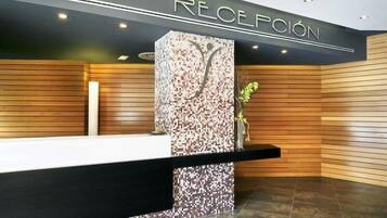 Un espace d’accueil doté d’un comptoir noir, d’un mur en mosaïque et de lambris en bois.