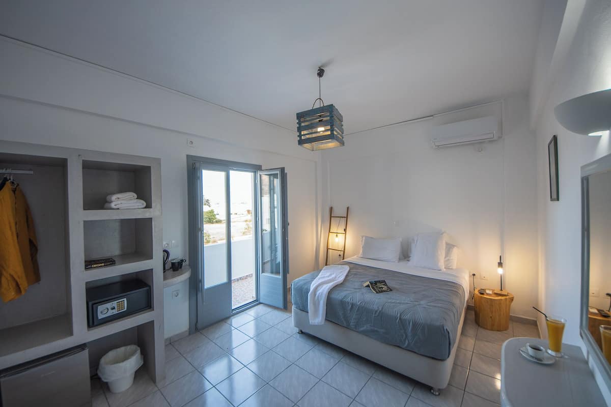 Quarto de hotel moderno com cama, guarda-roupa, banheiro e varanda.