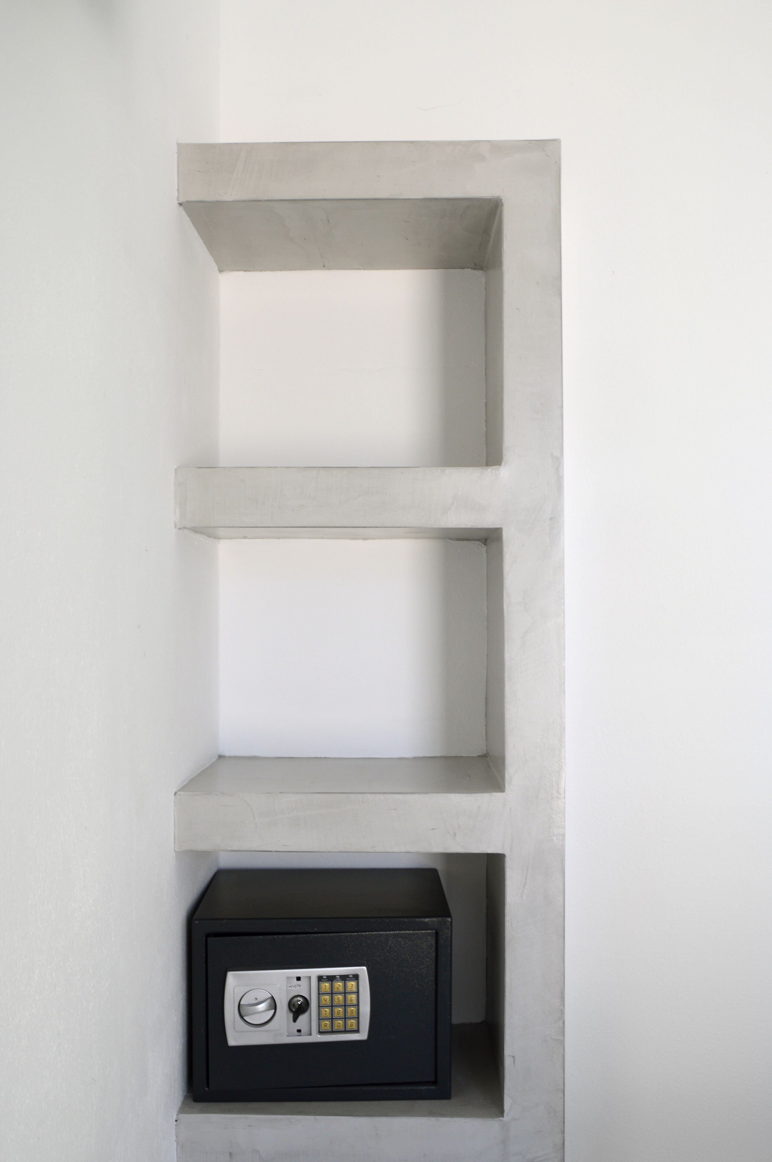 Een minimalistisch, wit interieur met een inbouwkluis in het onderste gedeelte.