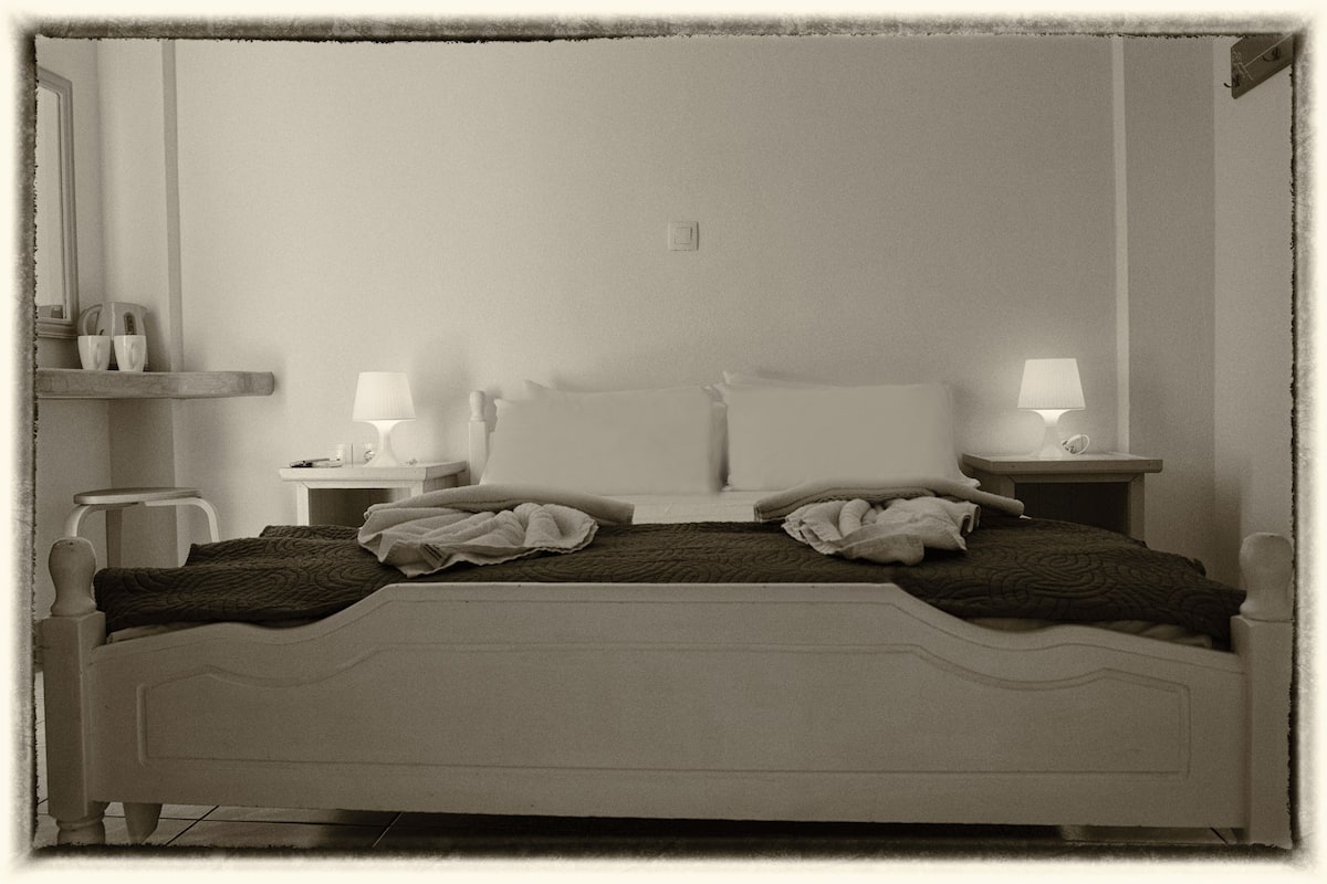Uma cama de dossel branca com duas mesas de cabeceira, cada uma com uma luminária.