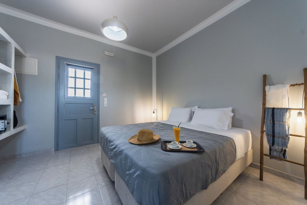 Quarto de hotel com cama, guarda-roupa, porta e janela.