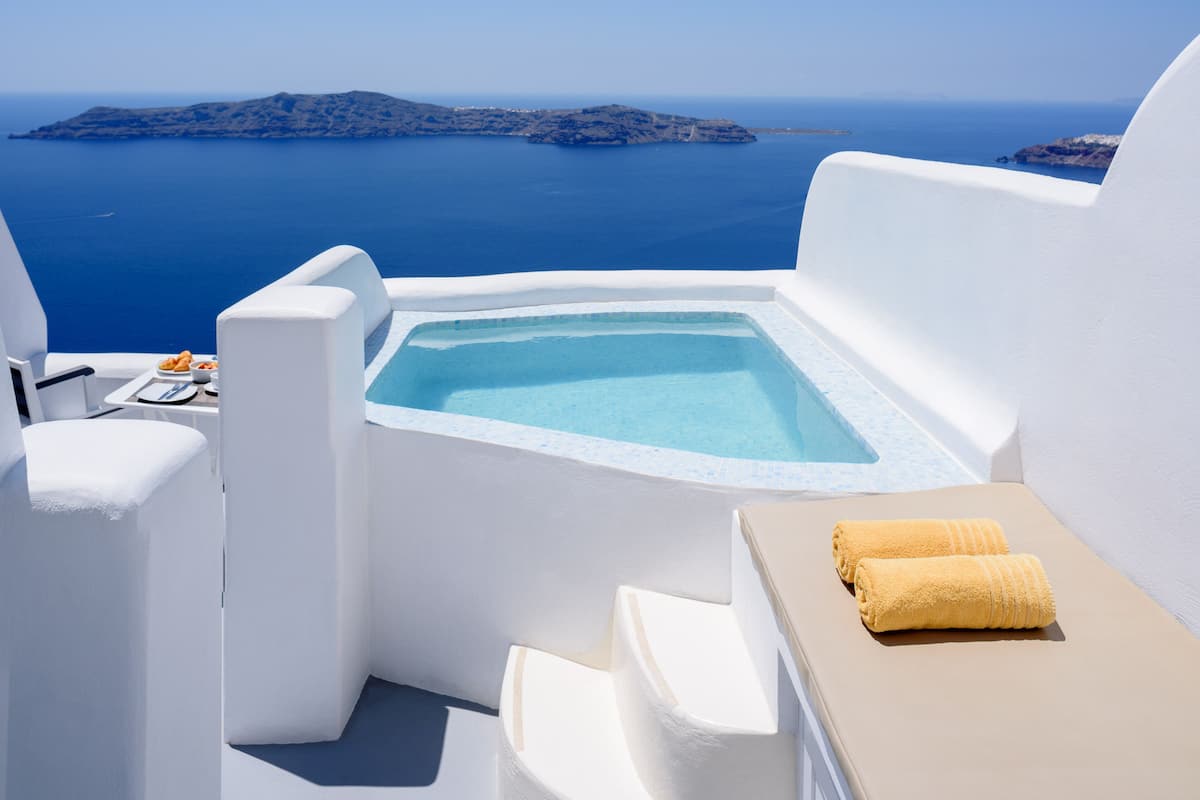 A white infinity pool with a clear view of the sea and islands in the background.