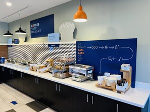 Zona de esmorzars amb un taulell que mostra diferents aliments i una pissarra amb les opcions de l'esmorzar.