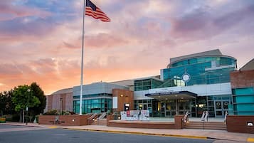A modern building with a glass facade, a prominent American flag, and a sign for the National Steinfeld Center.