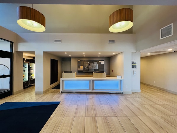 A reception area with a counter, two pendant lights, a refrigerator, and a wooden floor. - Holiday Inn Express & Suites Salinas by IHG (Salinas)