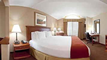 Una habitación de hotel con una cama grande, mesitas de noche, un escritorio y una silla.