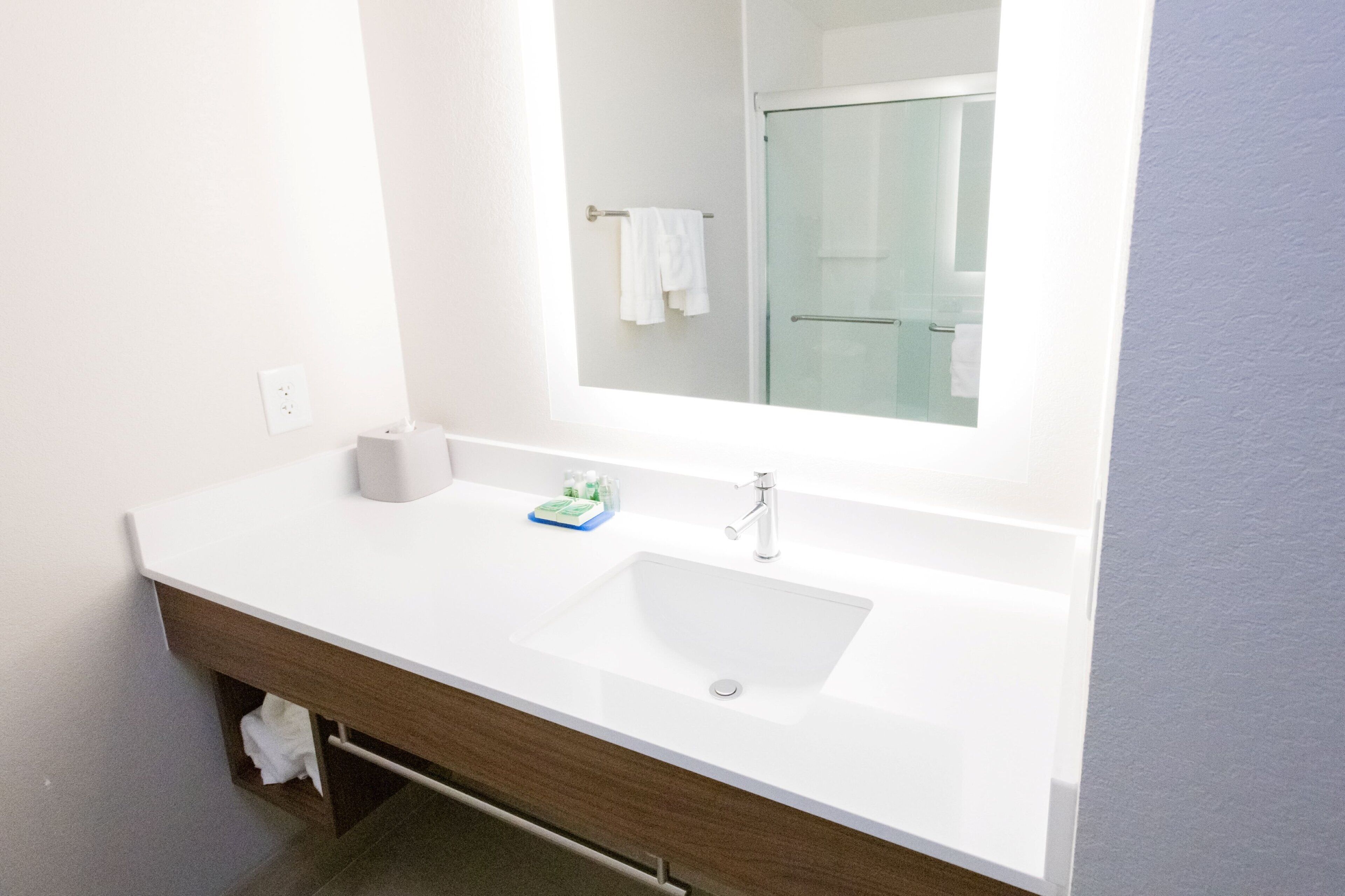 Une salle de bain moderne avec un lavabo blanc, un miroir et une cabine de douche en verre.