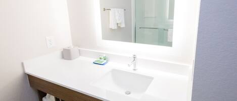 Une salle de bain moderne avec un lavabo blanc, un miroir et une cabine de douche en verre.