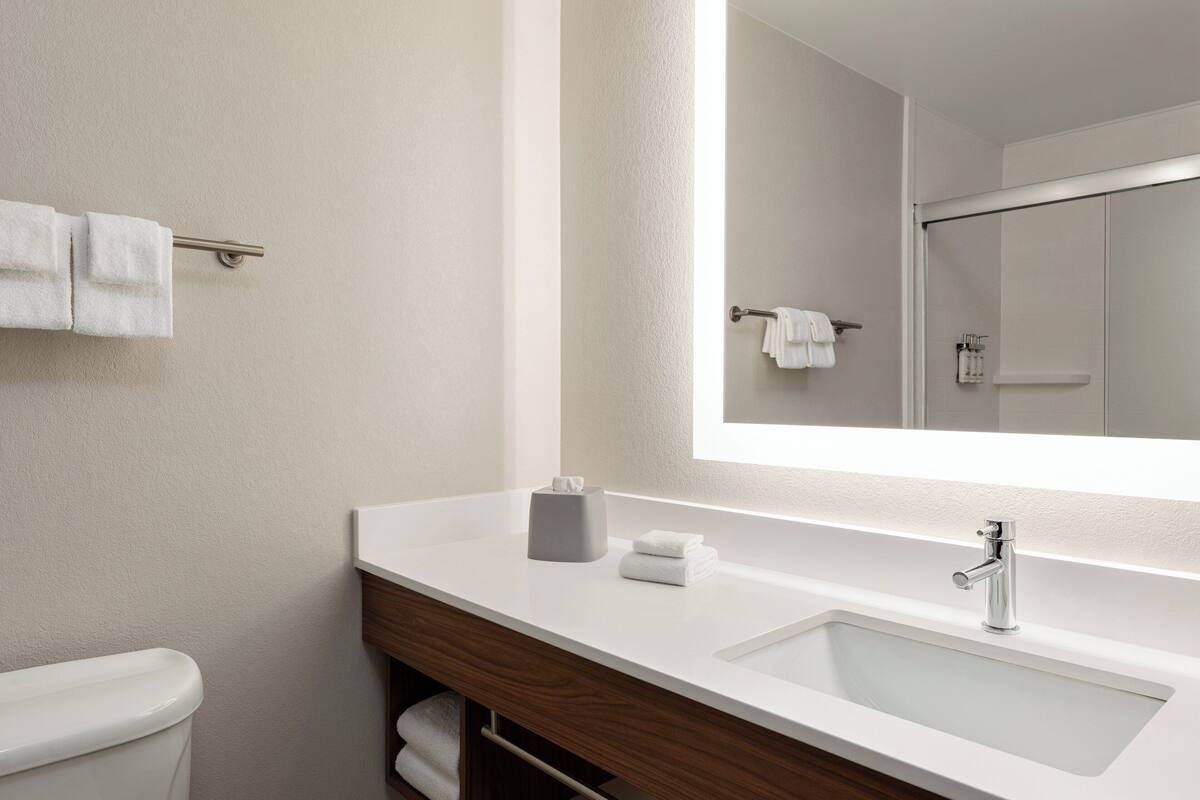 A modern bathroom with a white sink, a mirror, and a towel rack.