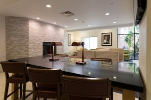 A modern kitchen with a large island, bar stools, a built-in oven, and a stone accent wall.