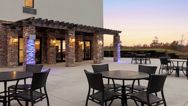 An outdoor patio area with stone pillars, tables, and chairs.