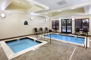 Una piscina con dos carriles, una zona de estar con sillas y una puerta que da al exterior.