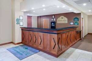 Una zona de recepción con un mostrador de madera, una pantalla digital y certificados enmarcados en la pared.