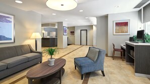 Un moderno vestíbulo de hotel con un sofá, un sillón y una zona de escritorio.