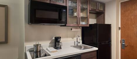 A compact kitchen with a microwave, coffee maker, dishwasher, and a refrigerator.