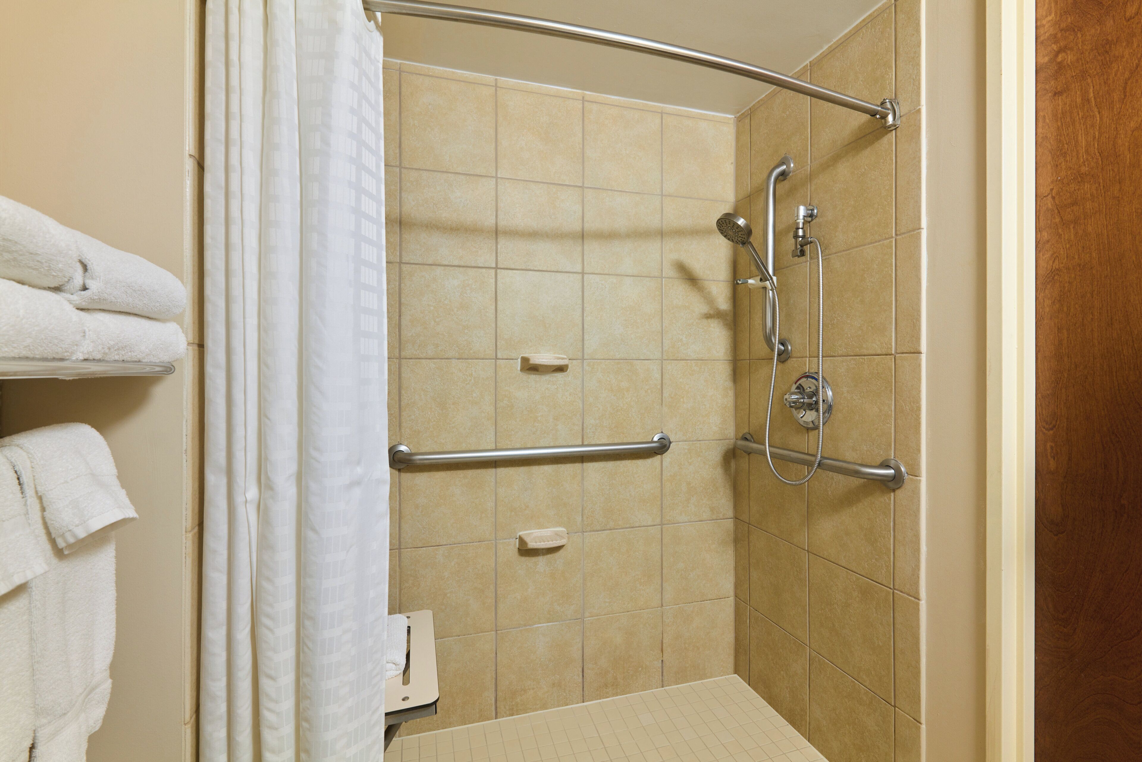 Un espace douche équipé d’une barre d’appui, d’un pommeau de douche à main et d’un porte-serviettes.