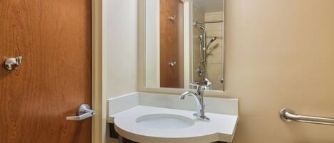 A bathroom with a wooden door, a white sink with a mirror above it, and a toilet.
