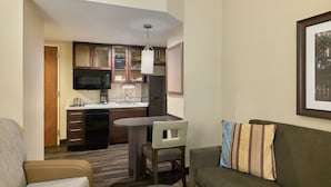 Un espacio habitable compacto con kitchenette, comedor y zona de estar.