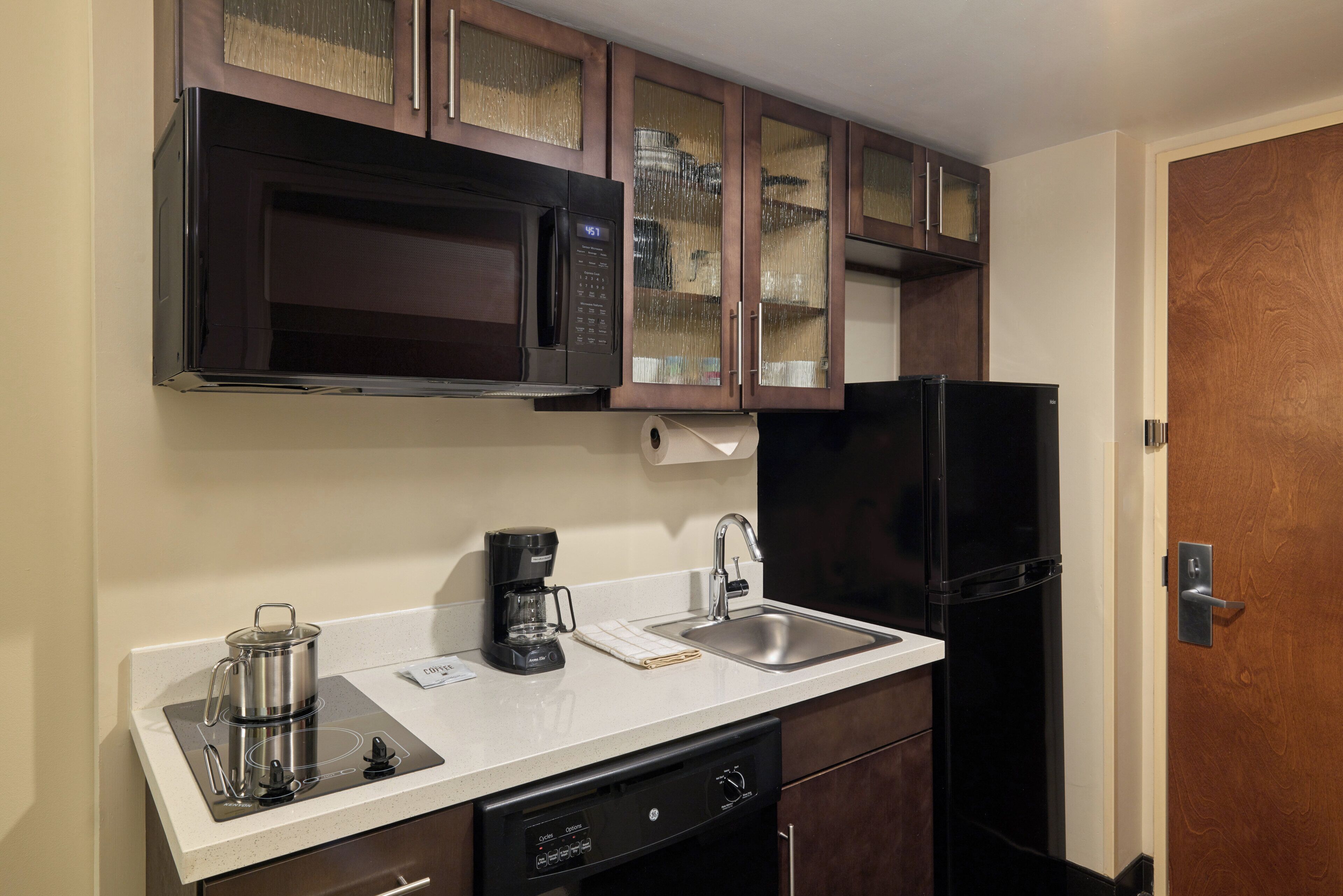 A compact kitchen with a microwave, coffee maker, sink, and dishwasher.