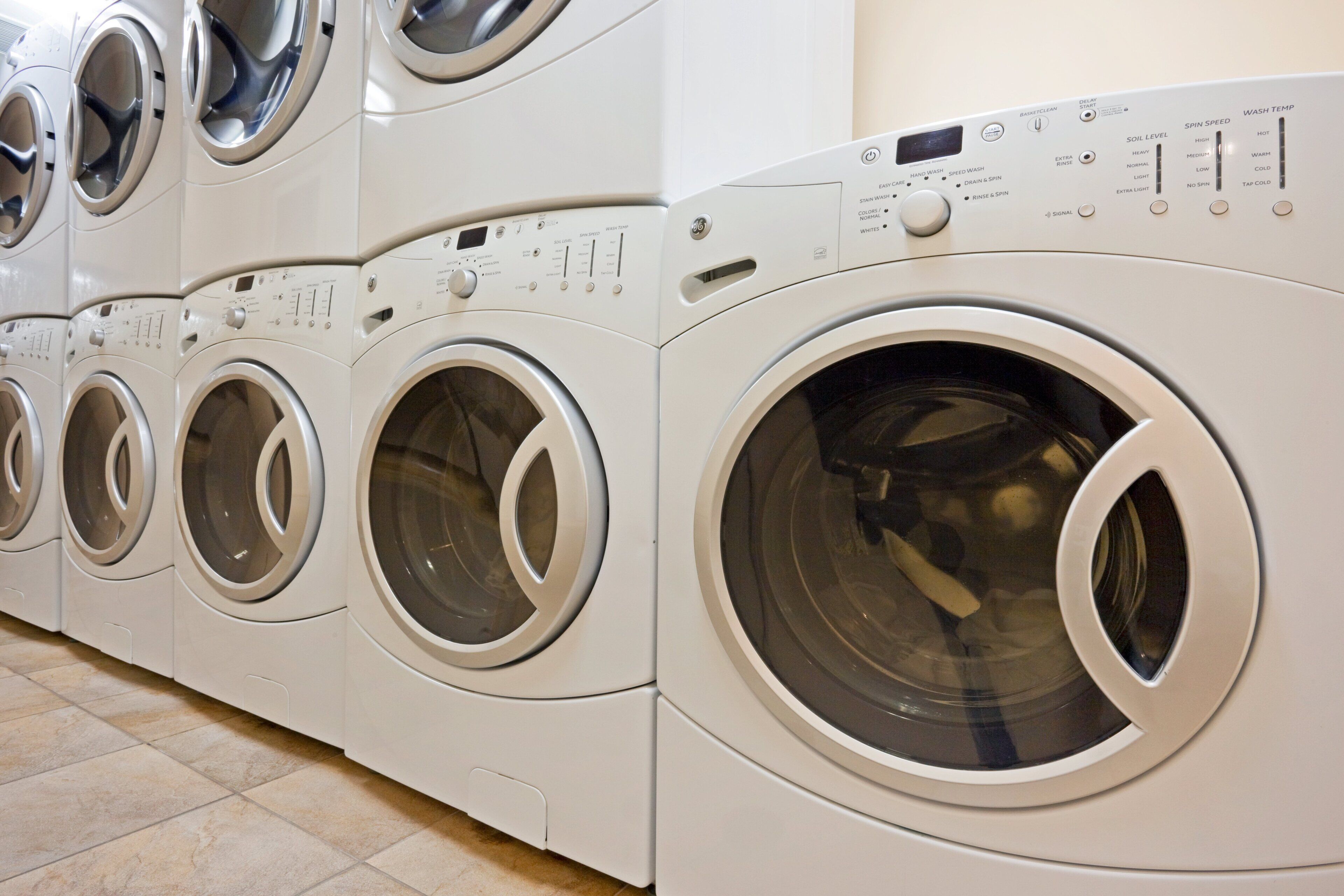 A row of front-loading washing machines in a commercial setting.