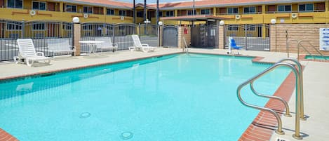 Una piscina al aire libre, sillones reclinables de piscina