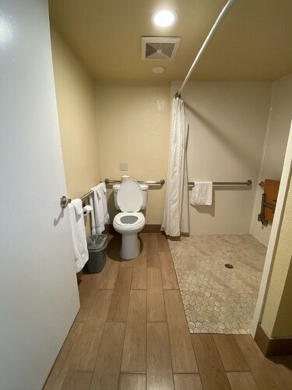 Une petite salle de bain compacte, dotée de toilettes, d’un espace douche et d’un sol carrelé.