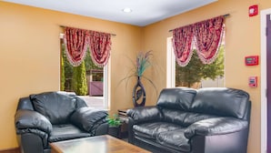A living room with two black leather sofas, a wooden coffee table, and a potted plant. - Americas Best Value Inn & Suites Mableton Atlanta (Mableton)