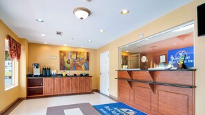 A hotel reception area with a coffee station, a reception desk, and a blue mat with the hotel's name. - Americas Best Value Inn & Suites Mableton Atlanta (Mableton)