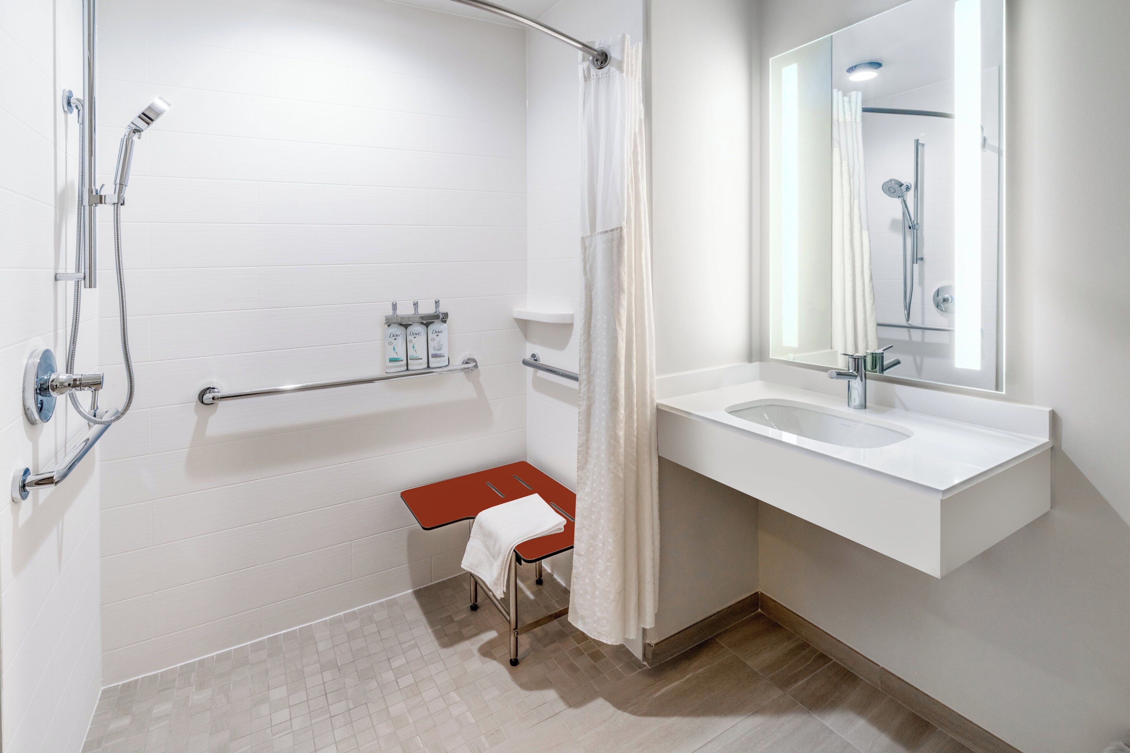 A modern bathroom with a shower, a toilet, a sink, and a mirror.