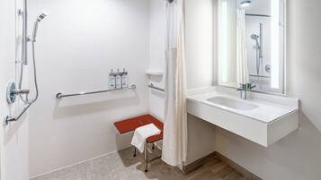A modern bathroom with a shower, a toilet, a sink, and a mirror.