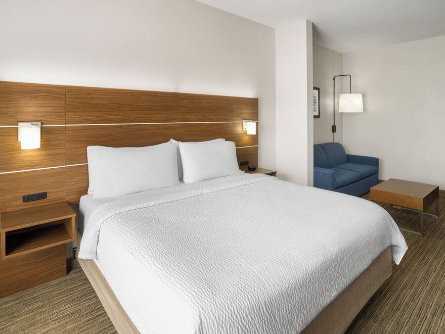 Una habitación de hotel con una cama grande, mesitas de noche, un escritorio, una silla y una lámpara.