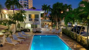 A swimming pool with lounge chairs and a staircase leading to a building. - Soleado Hotel (Fort Lauderdale)